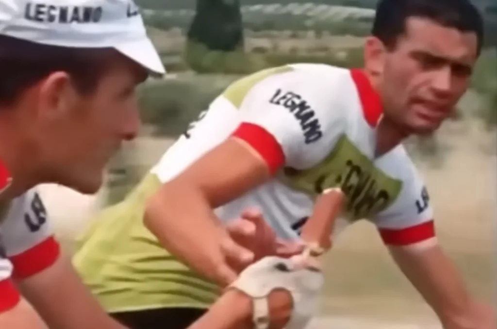 A Tour de France athlete offering a popsicle to his teammate.